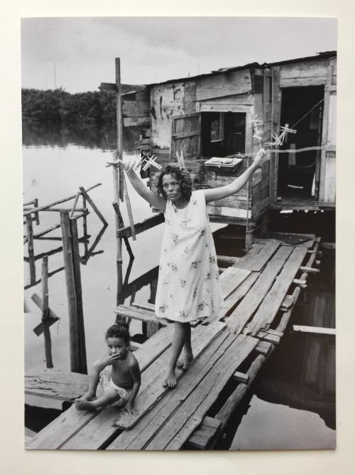 Woman holding on to clothesline with a child sitting on the deck, Puerto Rico