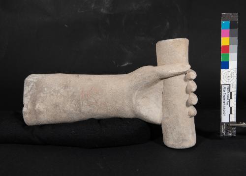 Left forearm and hand of a statue holding a scroll or container