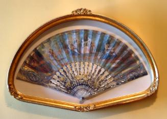 Fan with pastoral scenes in display case