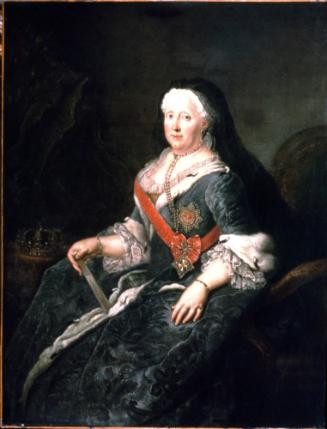 Older woman dressed in black gown with red sash and medal sits and looks out at the viewer