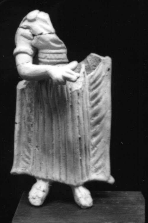 Female figurine in the pose of a lyre player wearing a belted short-sleeved tunic, cloak, sandals, and arm bracelet