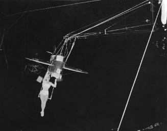 Les Krimi's aerial act with an airplane. Spectators watch the performance from the seats below.…