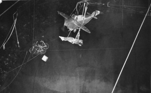 Les Krimi's aerial act with an airplane.  Spectators watch the performance from the seats below…