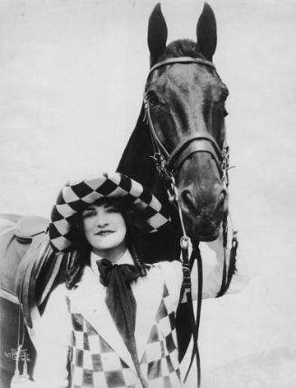 Woman in checked costume poses with horse