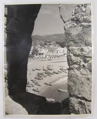 View of Mediterranean Shoreline with Fishing Boats Through Stone Archway
