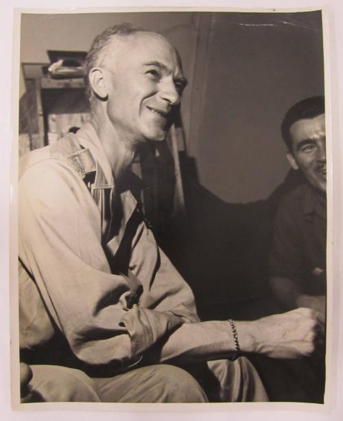 Balding Man Sits and Smiles in Conversation
