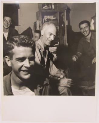 Young Man Smiles as Ernie Taylor Pyle Sits Enjoying a Coca Cola in the Middle Ground