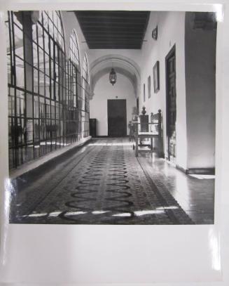 Hallway with Spanish Tile Floor Leads to Wooden Door