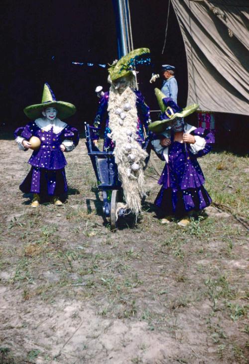 3 little people (midgets) in purple and green costumes