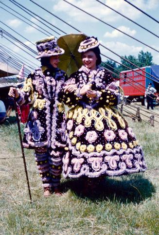 2 ladies in ornate black, pink, and yellow costumes