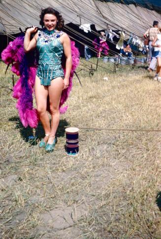 Lady in blue costume holding purple/pink headdress in BY